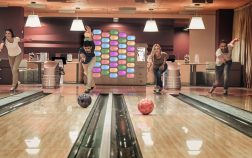 Happy young friends are having fun while playing bowling together